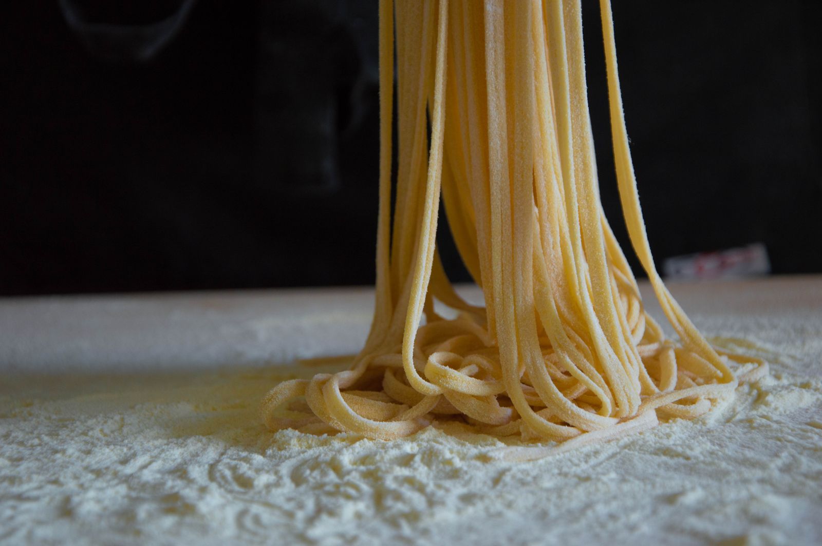 Close-up of fresh homemade pasta strands on a flour-covered surface, capturing the texture and craftsmanship.